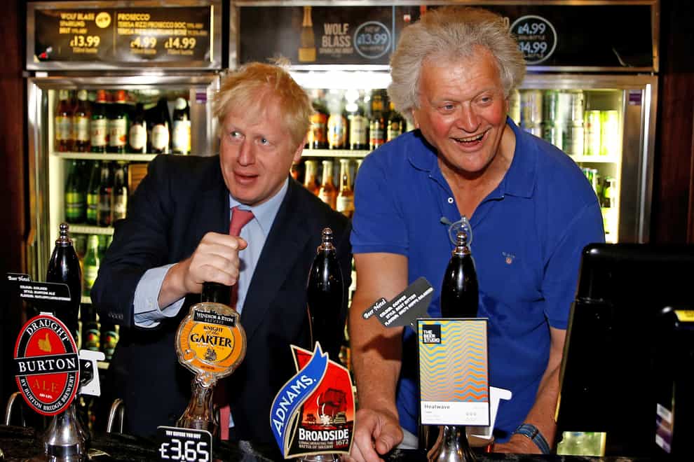 Tim Martin pulls a pint alongside Boris Johnson at a London Wetherspoon  pub last year. Now Martin has closed his pubs following the PM's direction (PA Images)