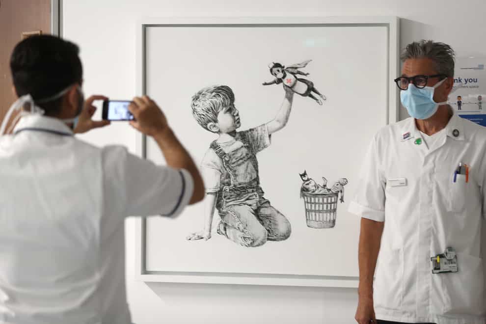A member of staff has their photograph taken in front of the new artwork by Banksy at Southampton General Hospital (PA Images)