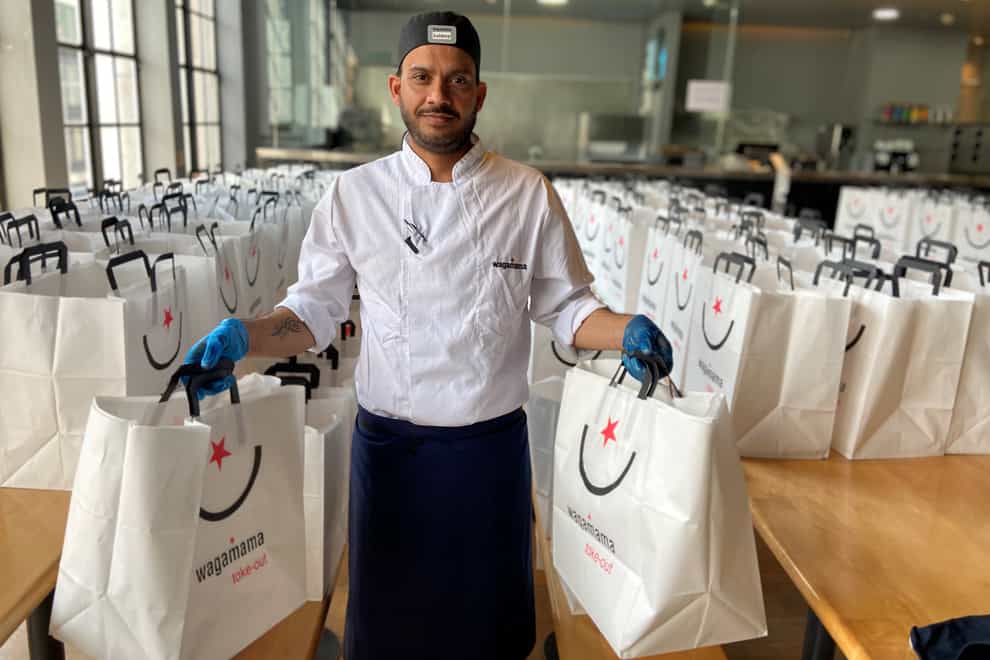 A Wagamama employee holding two takeaway bags