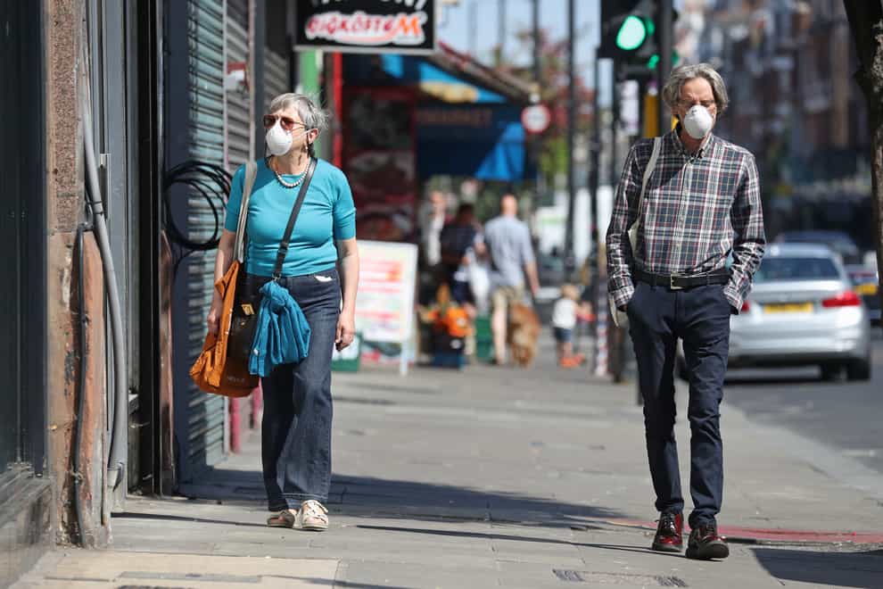 People wearing face masks walk past closed shops