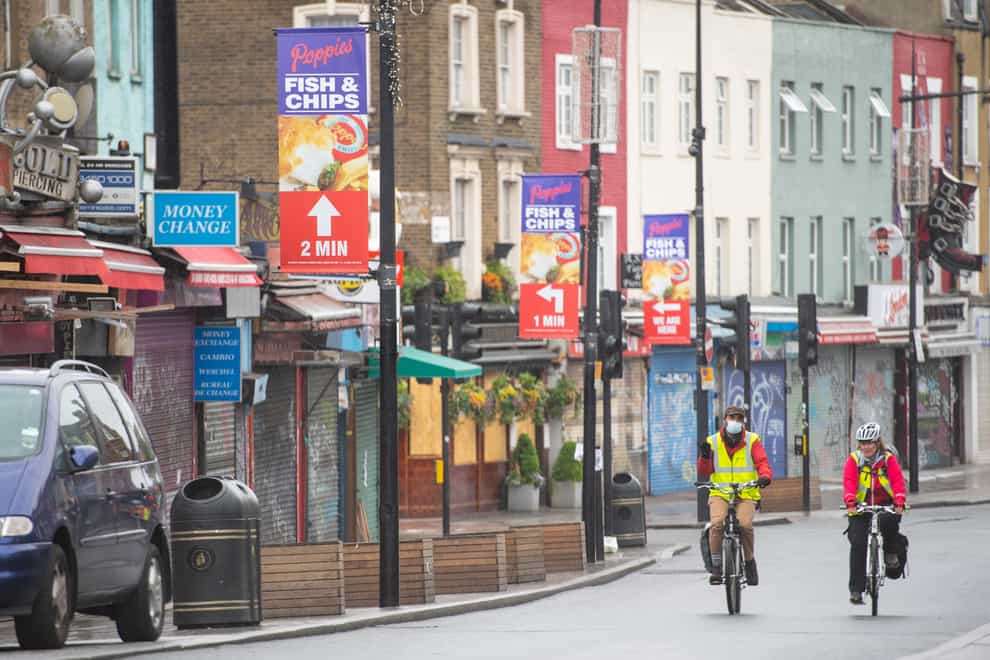 Cyclists ride past shuttered shops on Camden High Street in north London