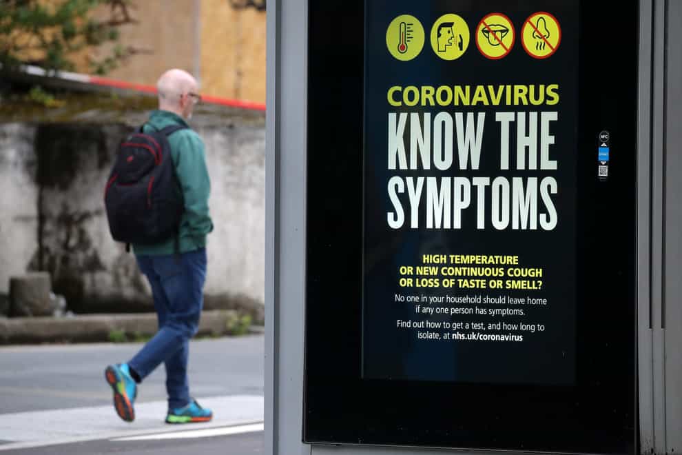 A person walks past an advertising board in Glasgow displaying a coronavirus-related message