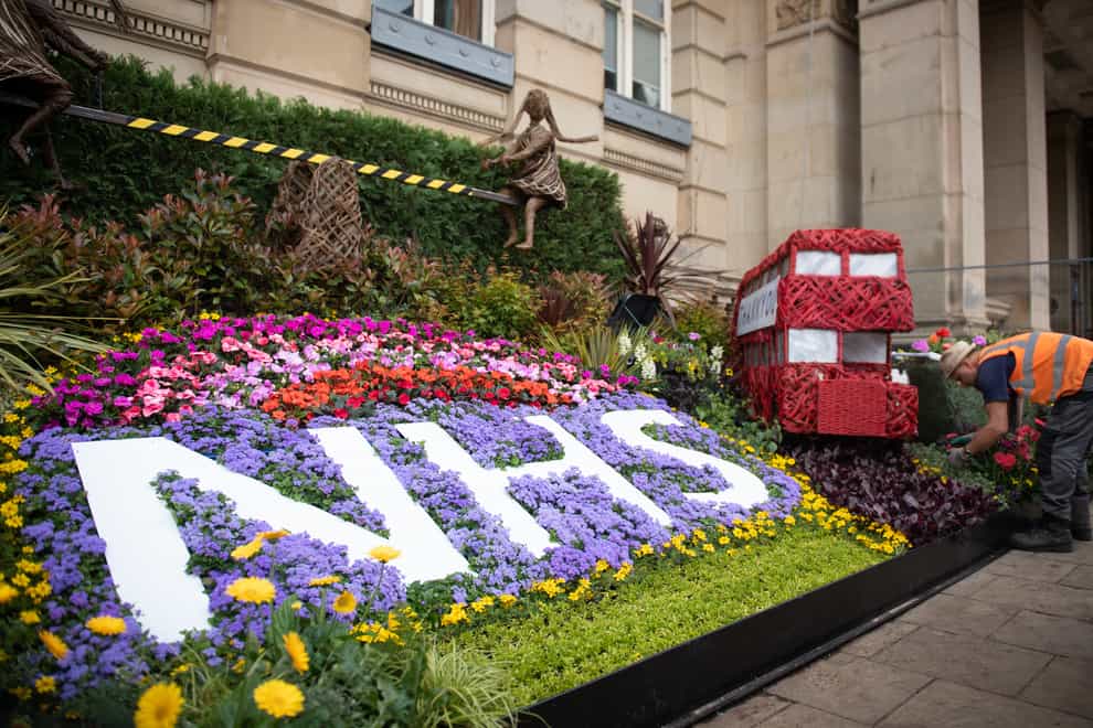 A gardener puts the finishing touches to a floral display thanking the NHS and key workers