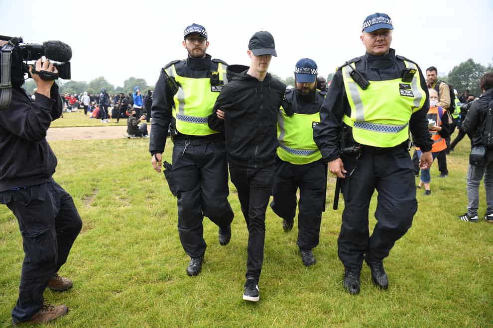 Police officers escort a man away from a Black Lives Matter protest rally in Hyde Park, London