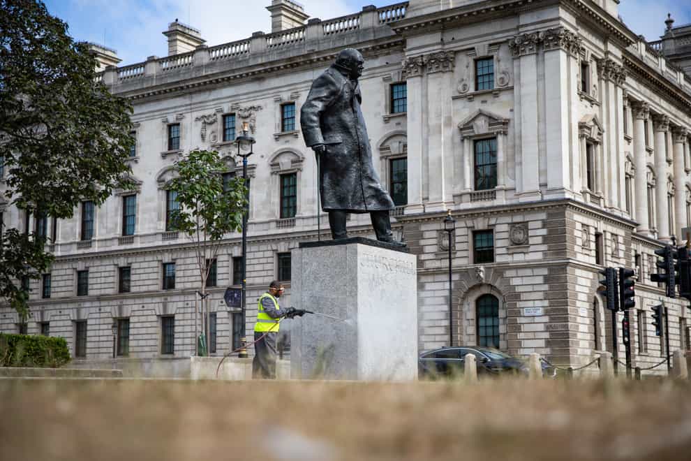 A worker cleans graffiti from the plinth of the statue of Sir Winston Churchill at Parliament Square in London