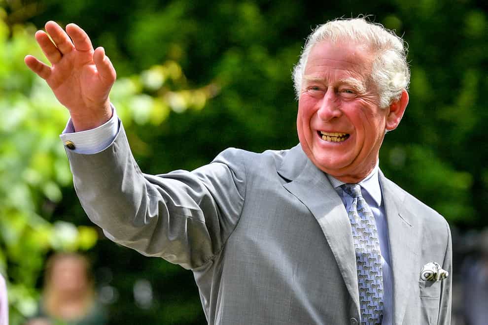 The Prince of Wales gestures to crowds of hospital staff watching from a distance at Gloucestershire Royal Hospital