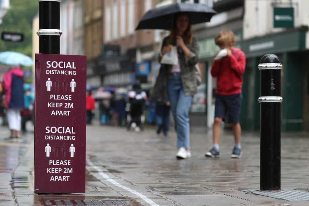 People walk past a social distancing sign