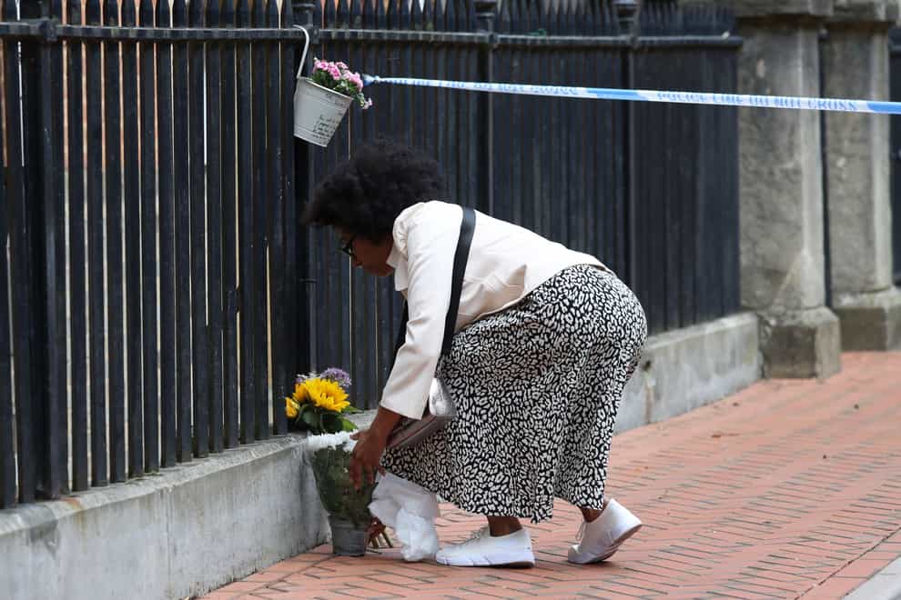 A woman places flowers at the Abbey gateway of Forbury Gardens