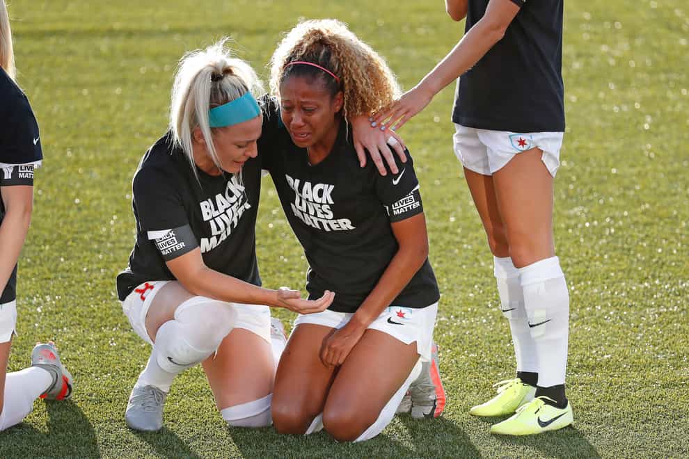 Julie Ertz puts and arm round Casey Short as they kneel together before Chicago's match against Washington
