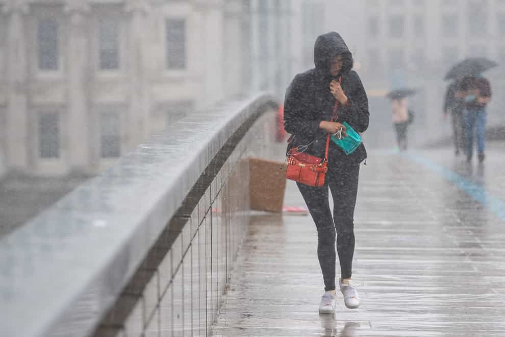 A woman runs to take shelter from a heavy downpour of rain on London Bridge