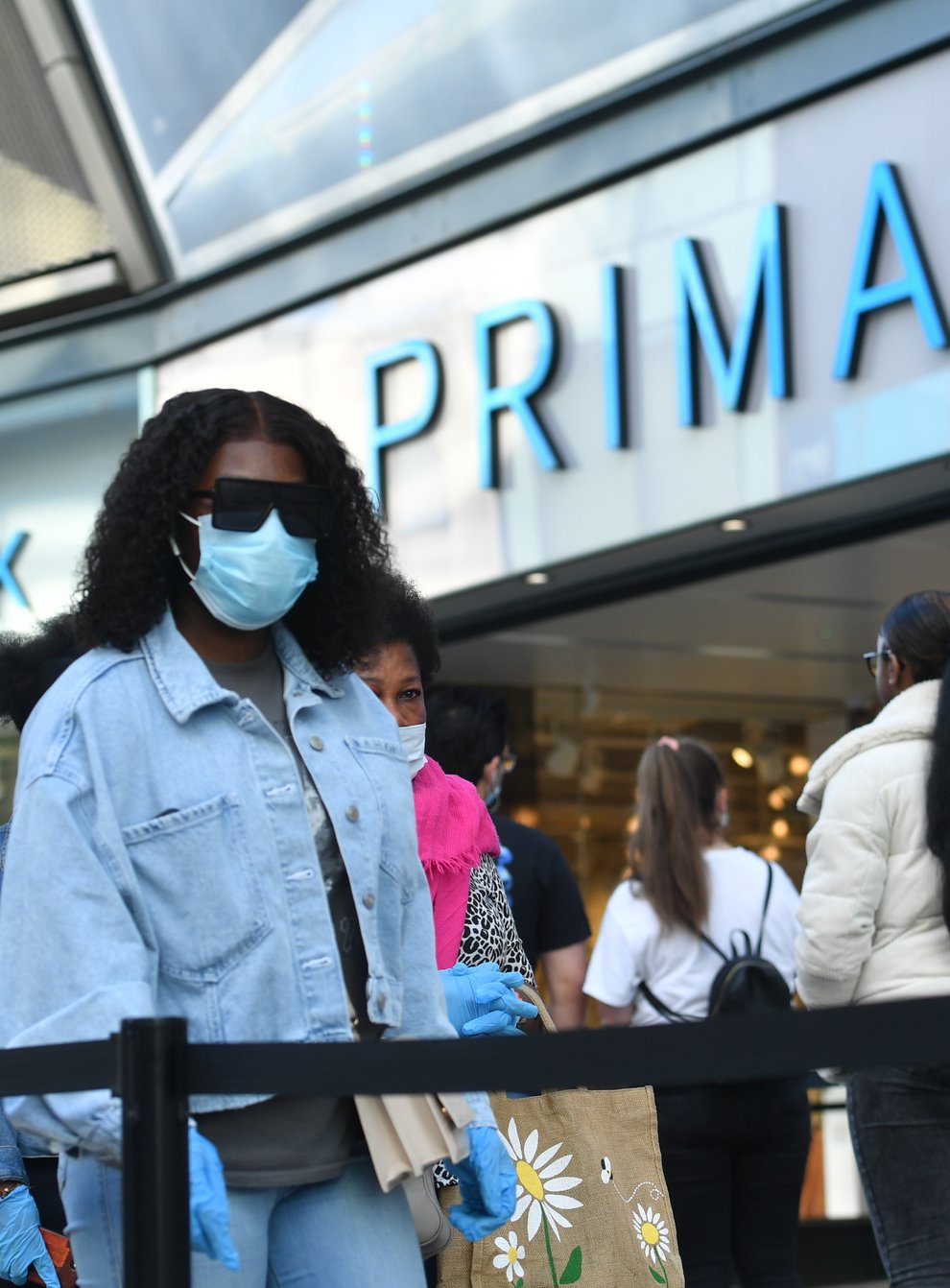 A woman wearing a face mask walks past a Primark store