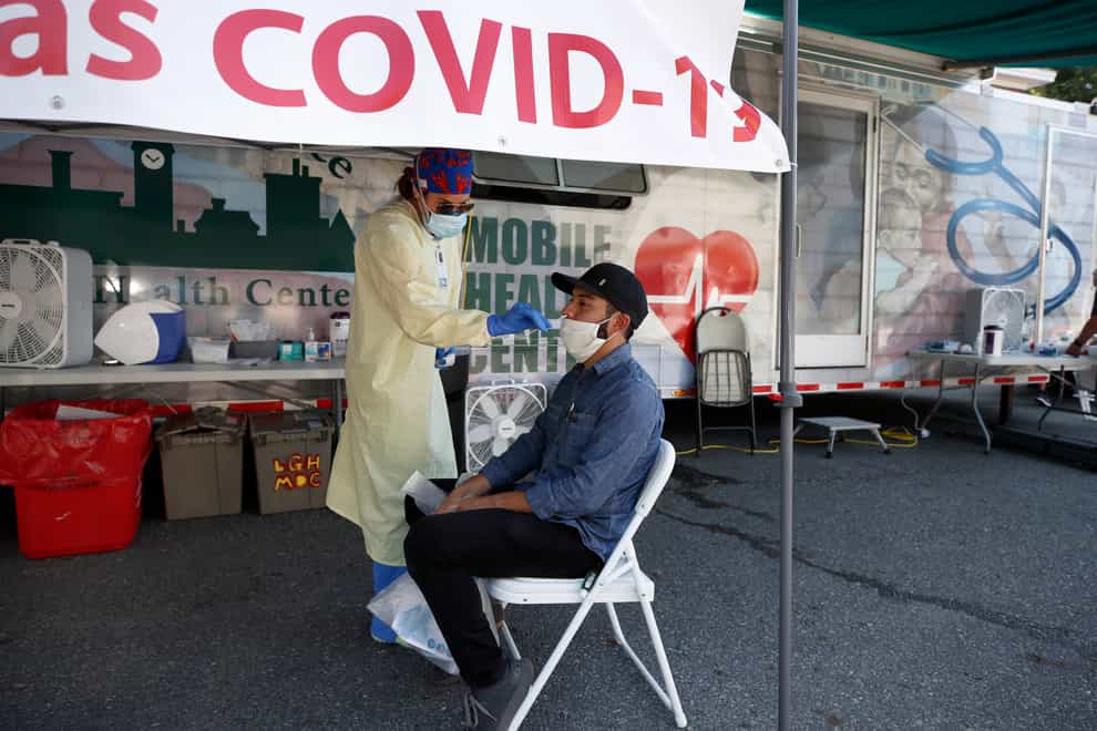Nurse Tanya Markos administers a coronavirus test on patient Ricardo Sojuel at a mobile COVID-19 testing unit in Massachusetts