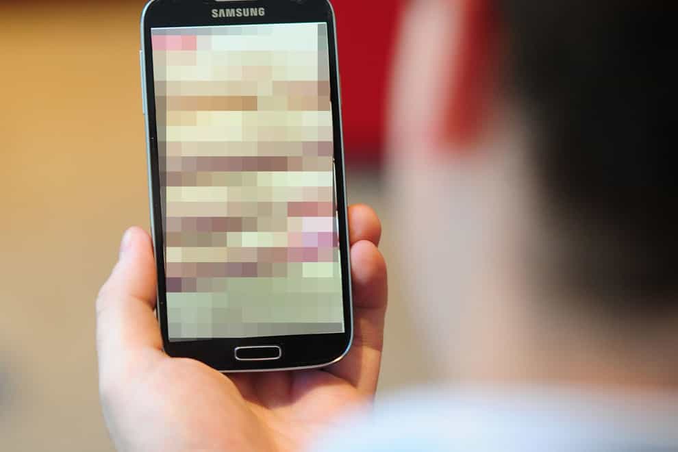 A man looking at a blurred screen on a mobile phone (PA)