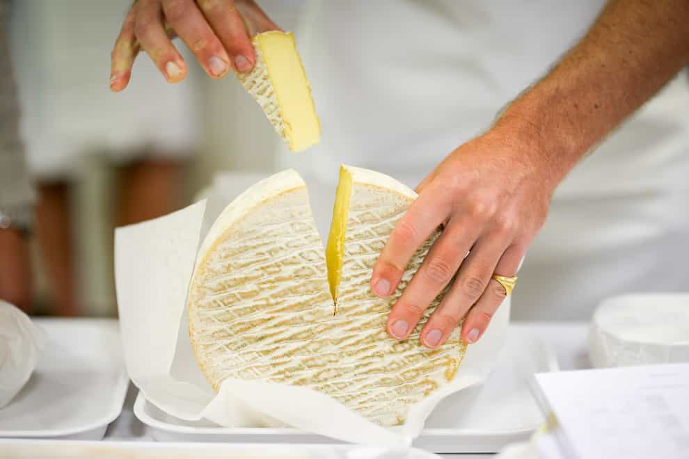 A slice of soft cheese is cut for tasting at the British Cheese Awards
