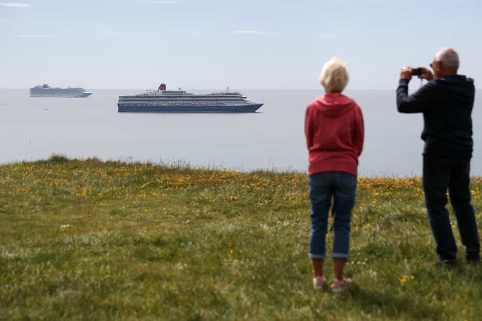 People look out towards two cruise ships in Dorset