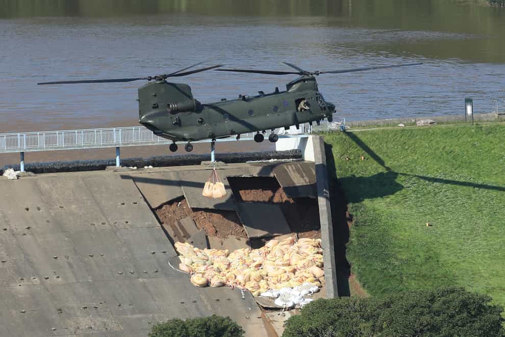 An RAF Chinook helicopter flies in sandbags to help repair the dam at Toddbrook reservoir