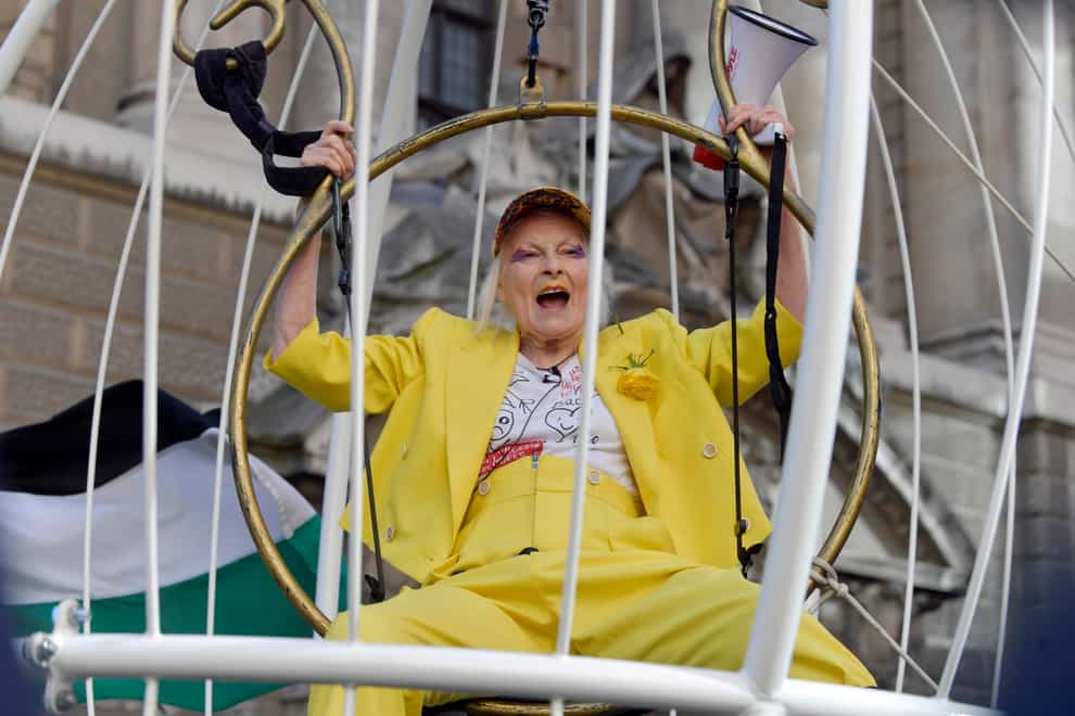 Dame Vivienne Westwood in a canary-yellow suit in a giant bird cage