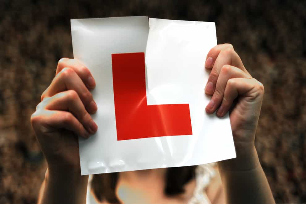 A woman holds up an L plate