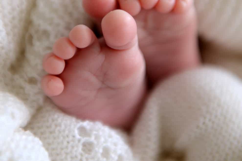 A new born baby’s feet are visible peeking out of a shawl (Andrew Matthews/PA)