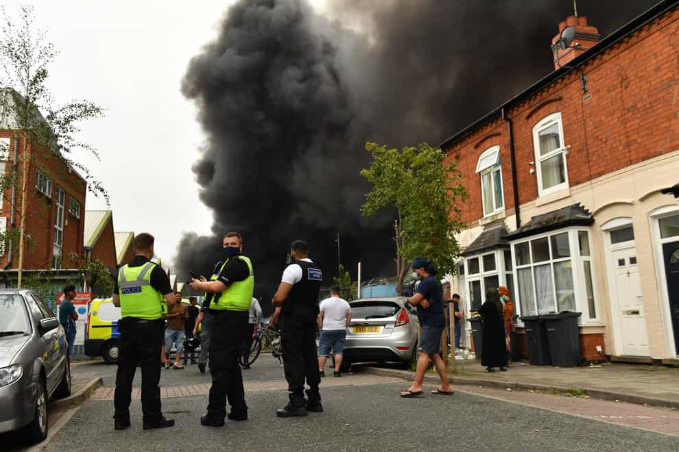 Police and local residents watch on as smoke billows from a severe blaze on an industrial estate in Birmingham