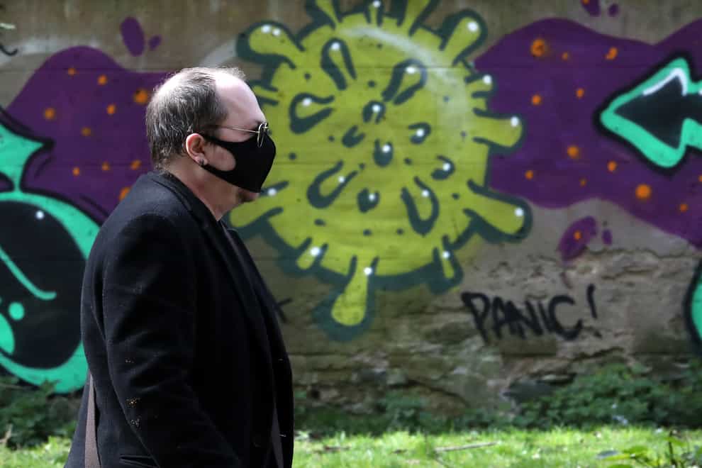 A man wearing a mask walks past coronavirus-related graffiti in Edinburgh