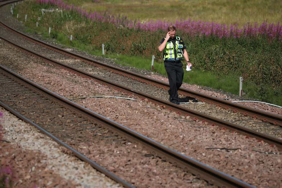 A police officer walks along the tracks at Carmont crossing, south of the scene in Stonehaven 