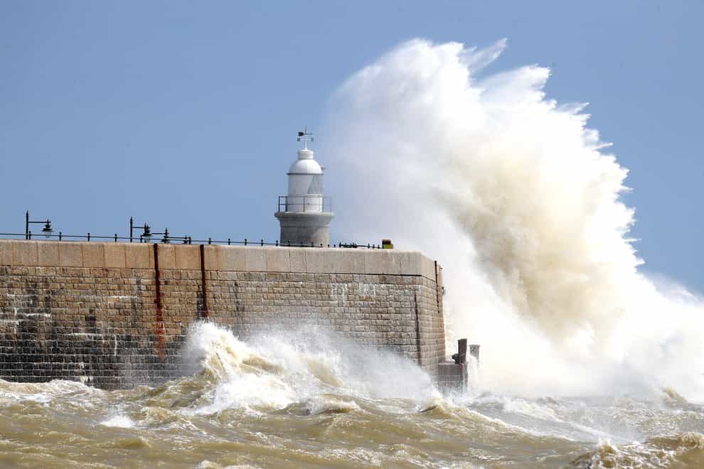 Waves crash over the harbour wall in Folkestone, Kent