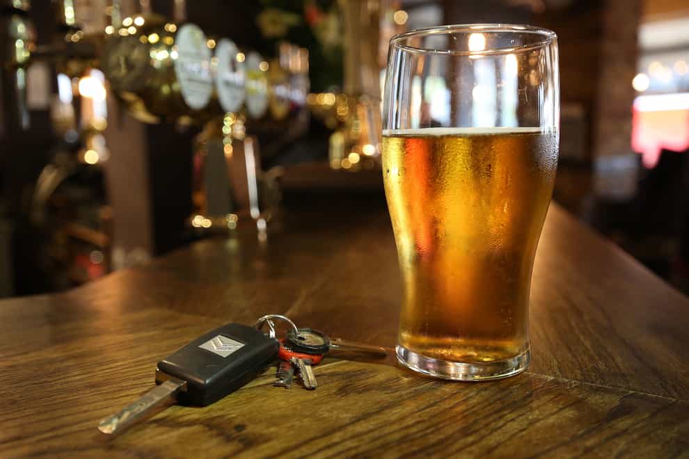 A set of car keys next to a pint of beer