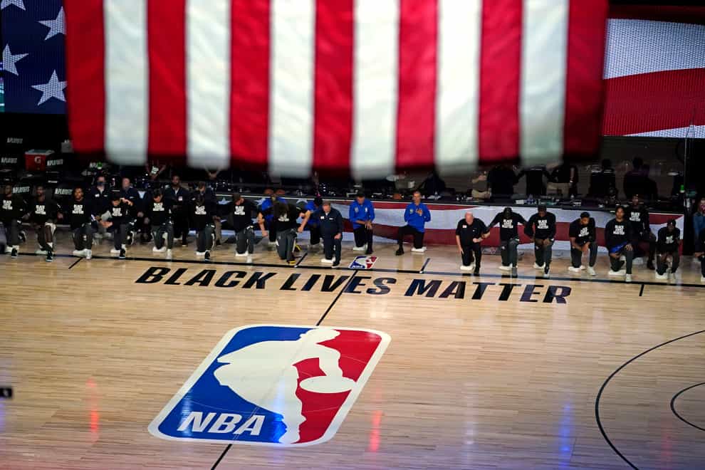 Members of the Milwaukee Bucks and Orlando Magic kneel during the national anthem before their NBA play-off clash