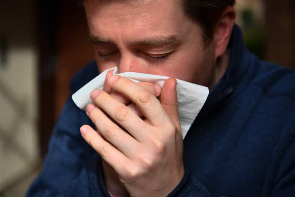 Man sneezes into a tissue