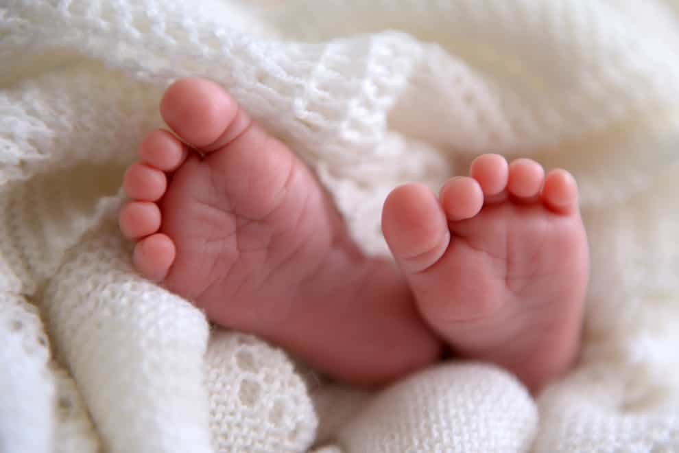 A new born baby’s feet are visible peeking out of a shawl (Andrew Matthews/PA)