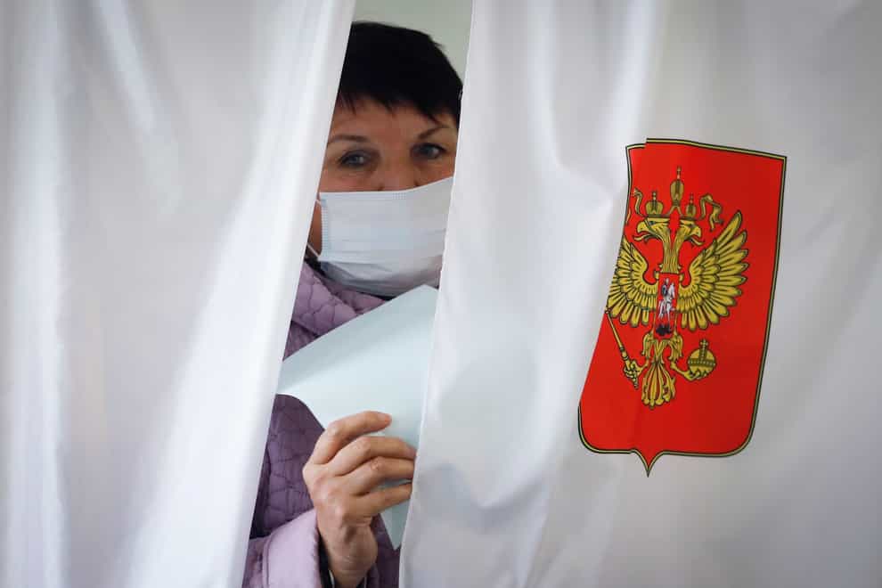 A woman wearing a face mask leaves a voting booth