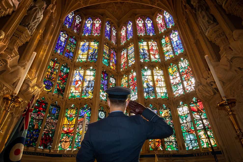 An officer salutes the Battle of Britain memorial window inside Westminster Abbey