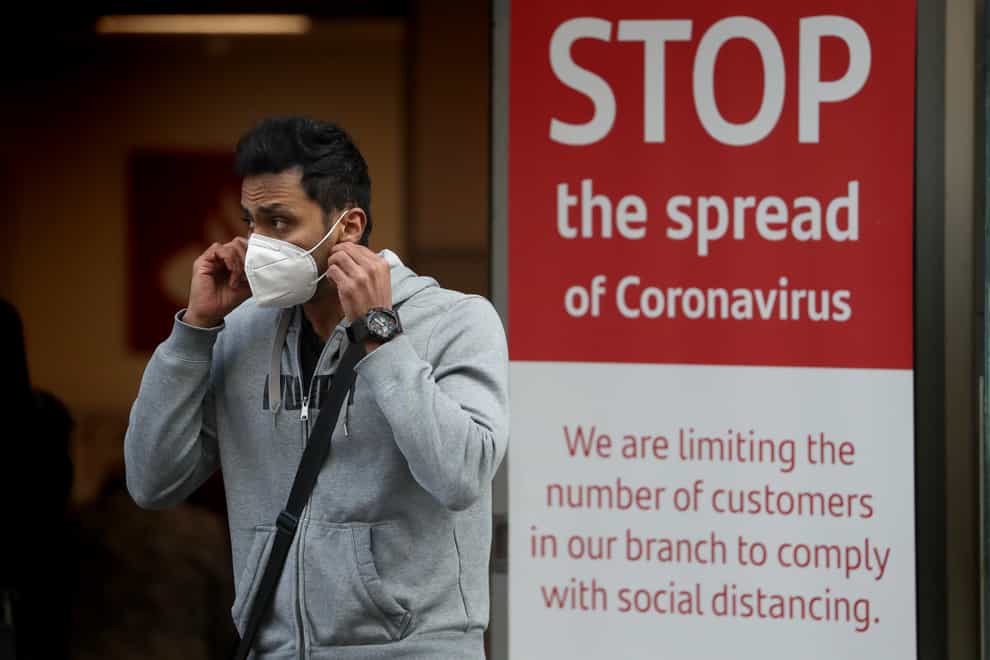 A man wearing face mask next to a coronavirus sign