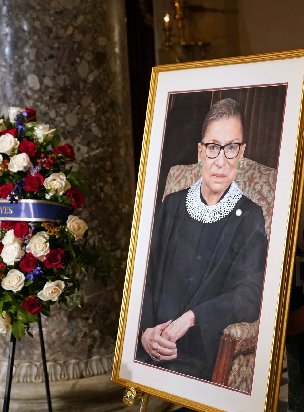 A staff member places a photo of Justice Ruth Bader Ginsburg before a ceremony for her to lie in state in Statuary Hall at the US Capitol
