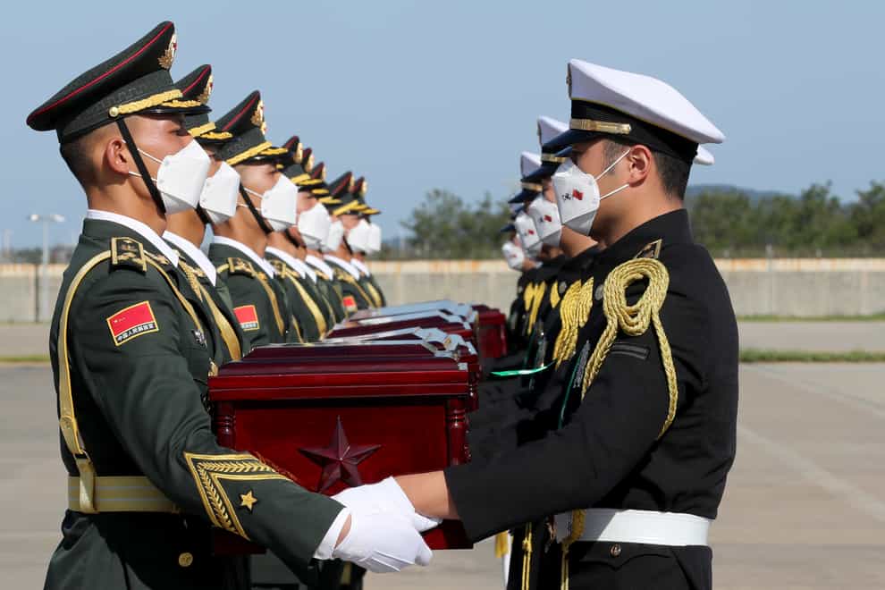 Chinese honour guard members, left, receive caskets containing the remains of Chinese soldiers from South Korean honour guards during the handing over ceremony at the Incheon International Airport in Incheon, South Korea