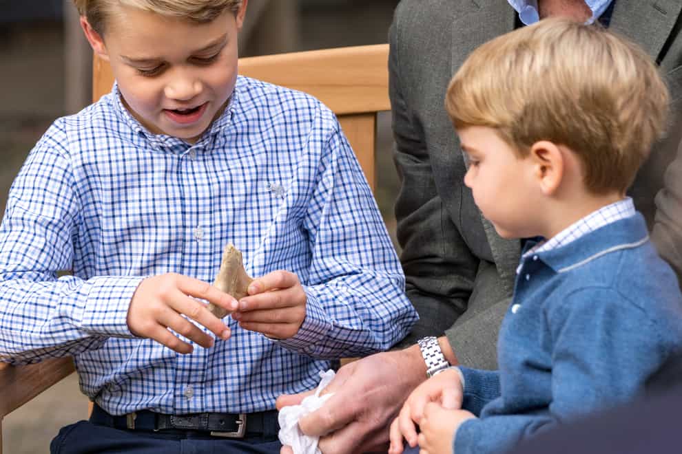 Prince George, with the Duke of Cambridge and Prince Louis, looks at his shark tooth, a present from Sir David Attenborough. Kensington Palace