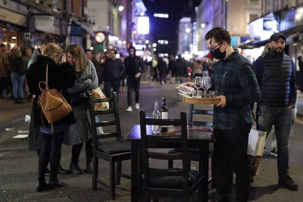 A member of bar staff clears a table in the street ahead of closing time