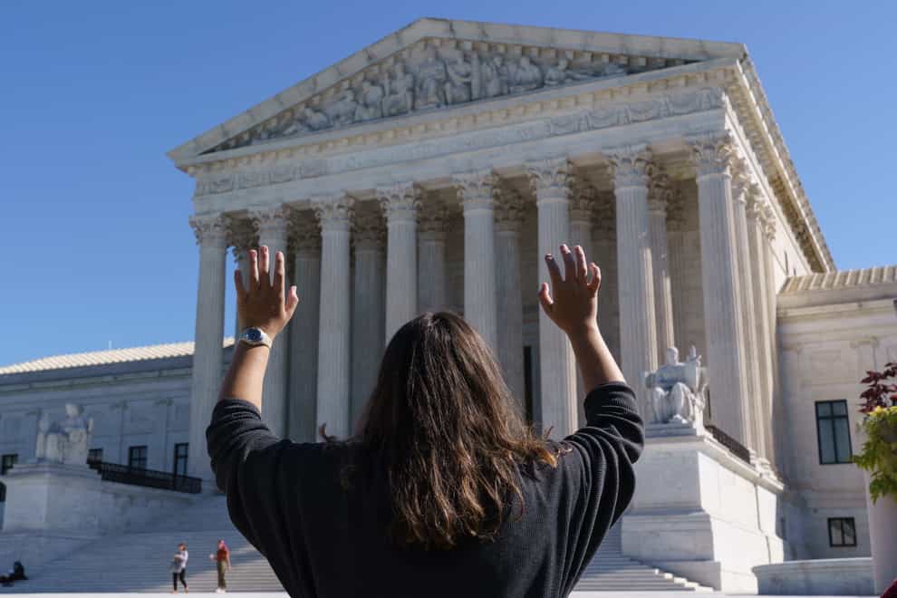 Megan Bixler of Tyler, Texas, holds out her hands in prayer as she and others from a Christian group, Youth With a Mission, sing at the Supreme Court in Washington, (J. Scott Applewhite/PA)