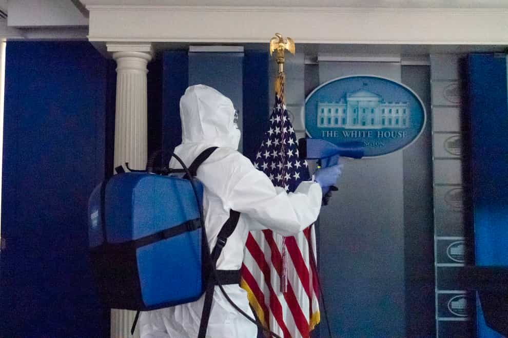 A member of the cleaning staff sprays The James Brady Briefing Room of the White House