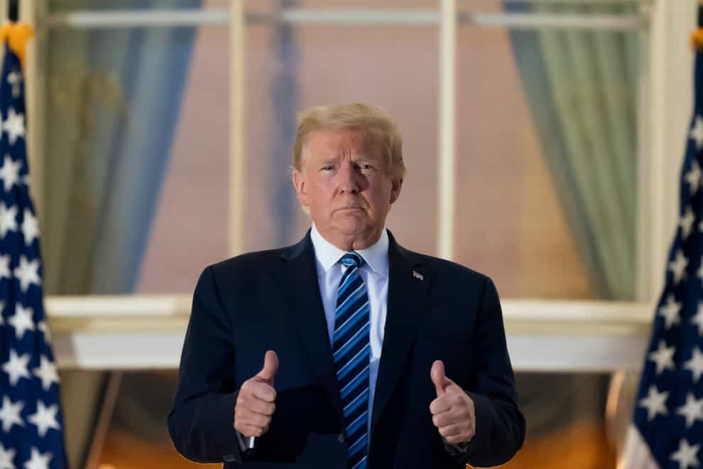 President Donald Trump gives thumbs up as he stands on the Blue Room Balcony upon returning to the White House