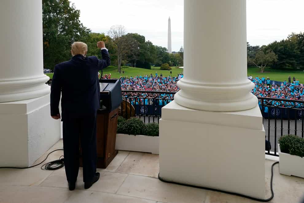 President Donald Trump gestures from the Blue Room Balcony of the White House (Alex Brandon/PA)