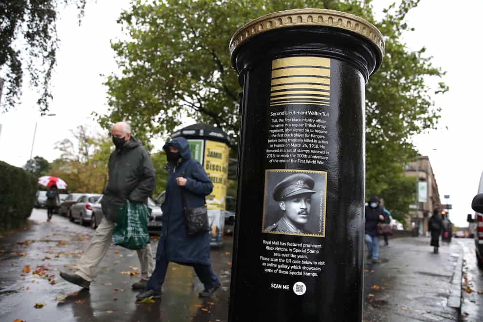 Members of the public walk past a black postbox featuring an image of Second Lieutenant Walter Tull, on Byres Road, Glasgow, one of four special edition postboxes unveiled by Royal Mail to mark Black History Month