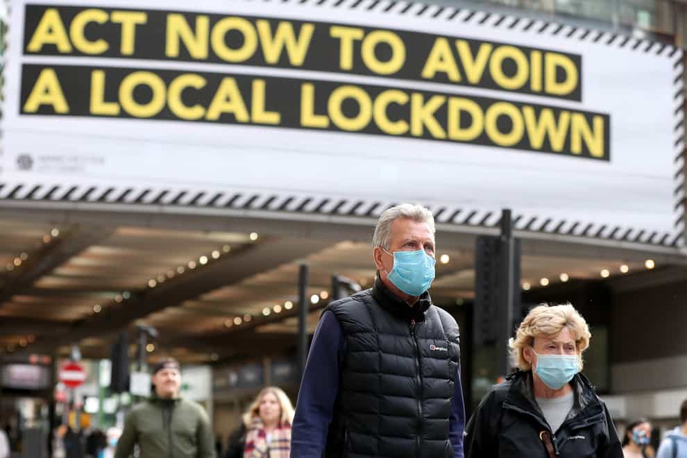 People wearing face masks walk past a local lockdown sign