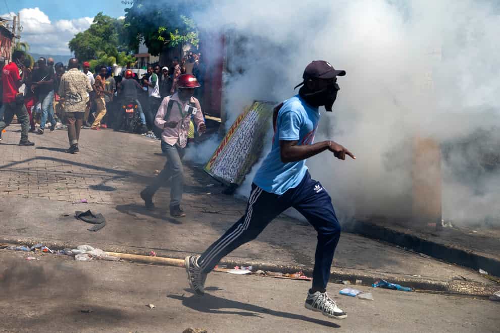Protesters run from tear gas launched by police to disperse protesters demanding the resignation of President Jovenel Moise in Port-au-Prince, Haiti (Dieu Nallo Chery/AP)