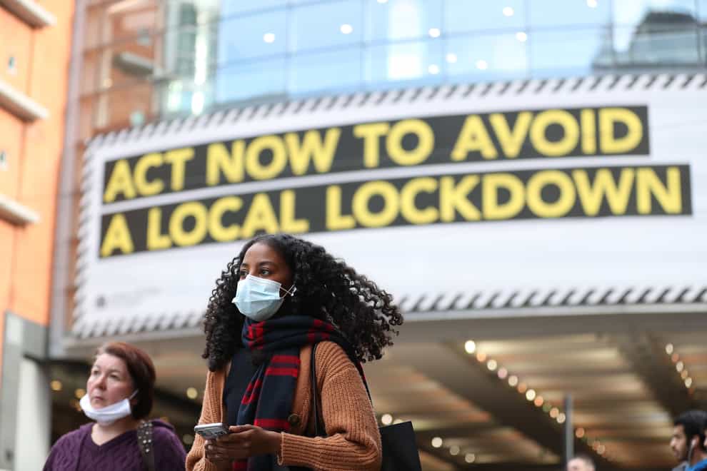 A woman wearing a face mask walks through Manchester (Martin Rickett/PA)