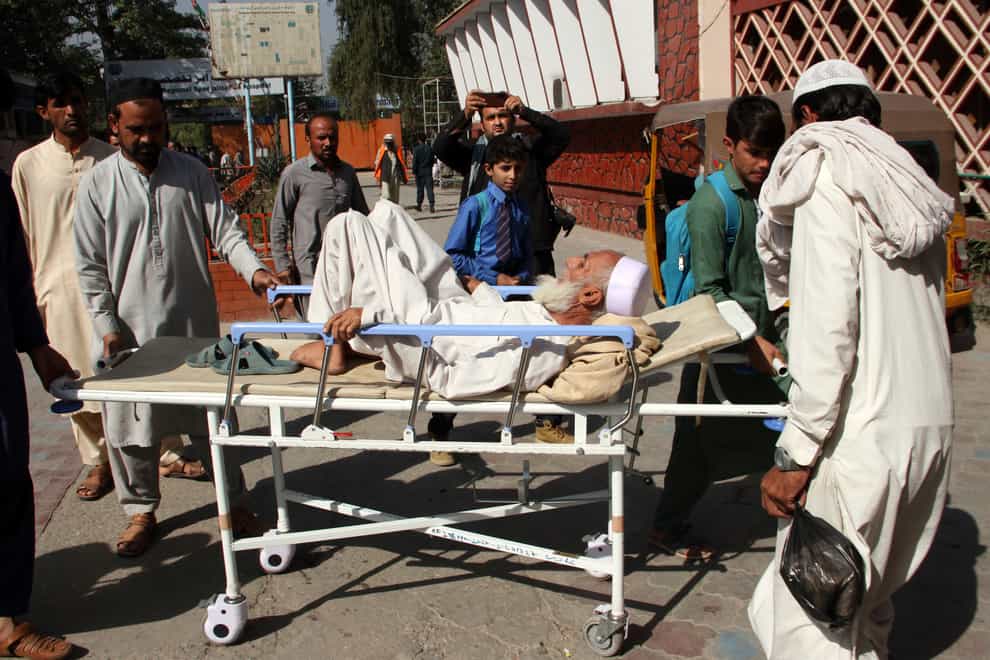 Afghans bring a man injured in a stampede to a hospital