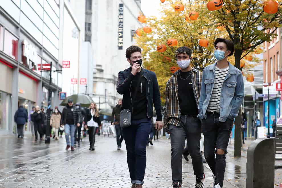 People wearing face masks walk down Market Street in Manchester