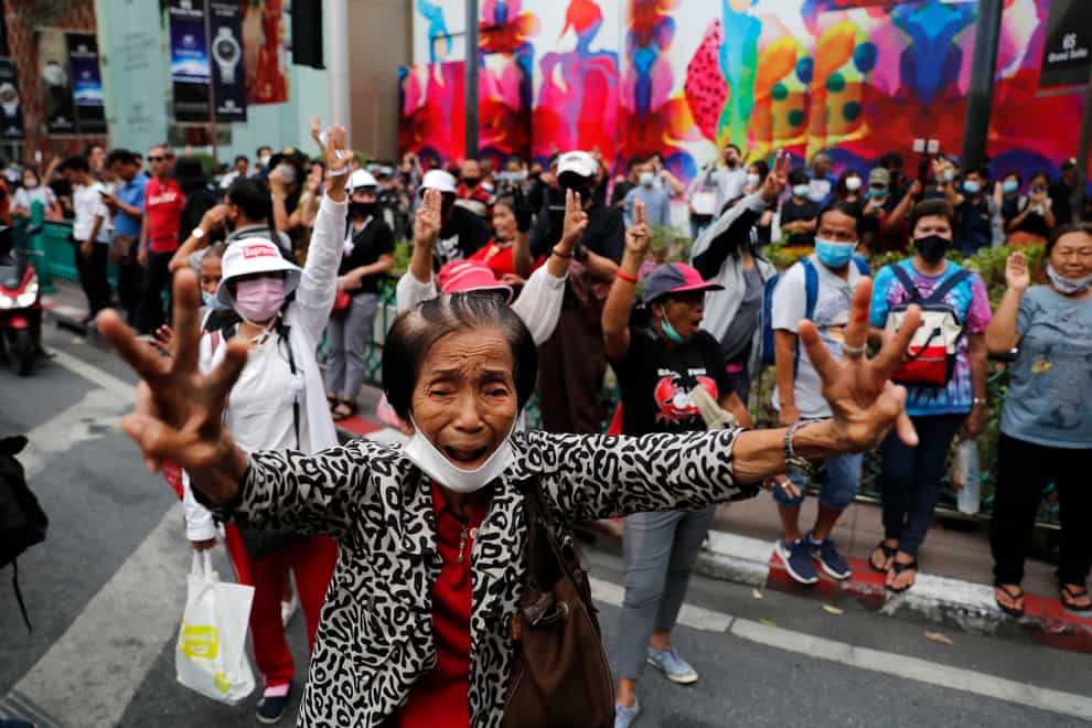 Pro-democracy protesters gather, flashing three-fingered salutes near a main shopping district in Bangkok