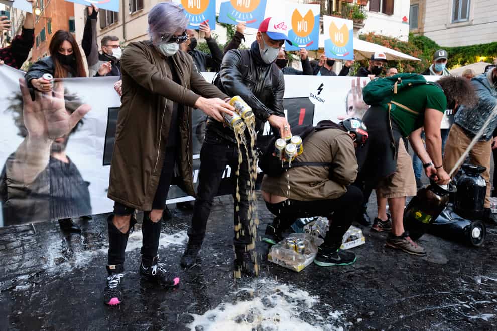 People spill beer on the ground during a protest against the government's new restrictions
